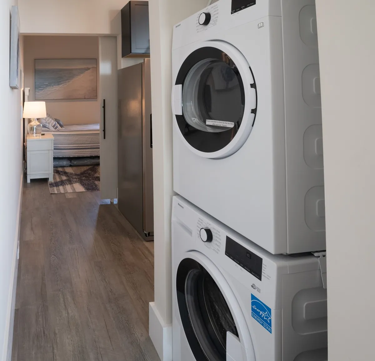 This interior image features a stacked washer and dryer, a doorway leading to a bedroom, and a nearby refrigerator, evoking a sense of practical convenience and well-organized storage. It exemplifies the easy access to essential tools for longer stays or family getaways.