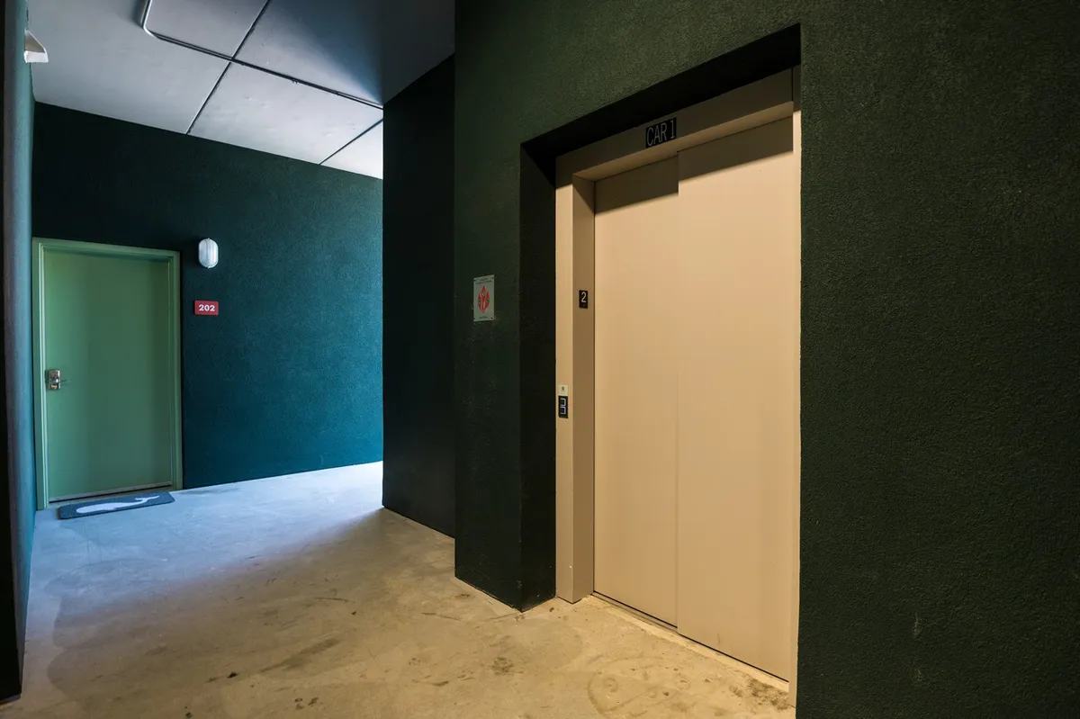 This image showcases a hallway with a prominent elevator and a green door. The clean, modern setting gives a glimpse of the secure, convenient access points within the building—ideal for arrivals and moving luggage easily. The elevator is an essential amenity for families, pet owners, and anyone seeking accessible vertical flow.